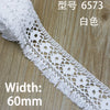 White cotton embroidered lace trim with a diamond pattern shown on a wooden surface.