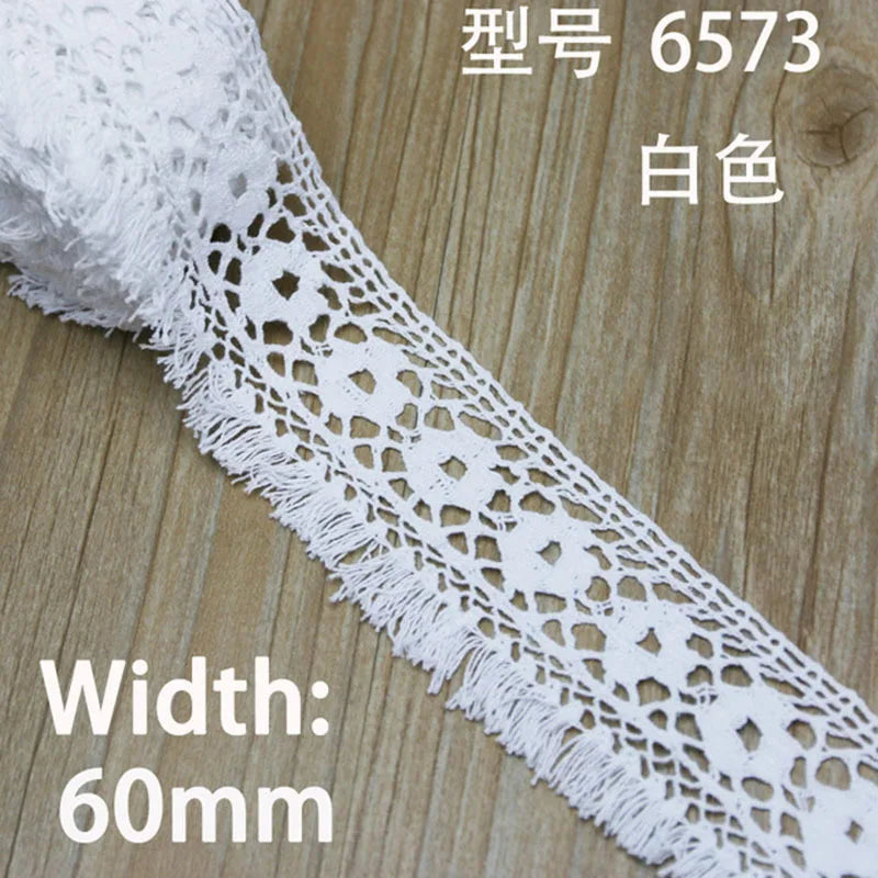 White cotton embroidered lace trim with a diamond pattern shown on a wooden surface.