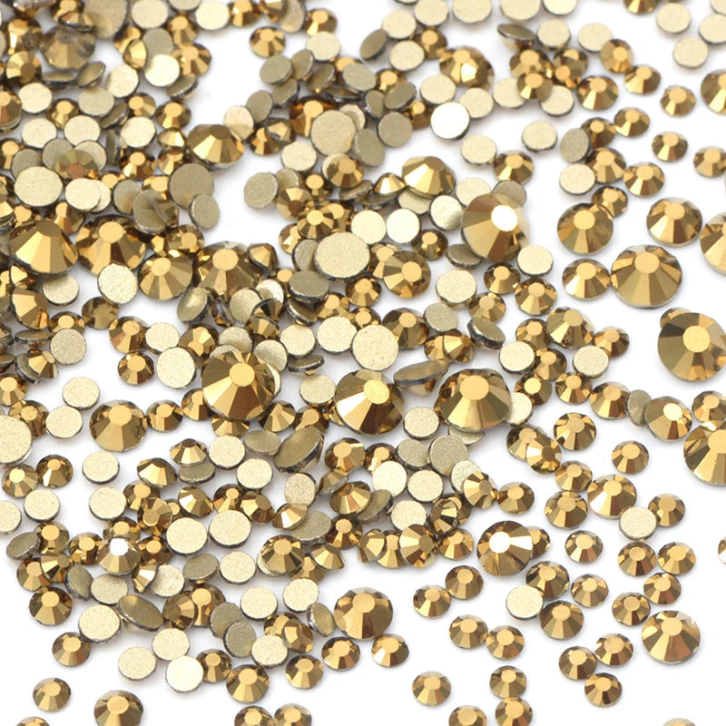 A pile of gold and bronze glass rhinestones for DIY crafts