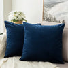 A dark navy blue velvet decorative pillow resting on a light beige fabric.