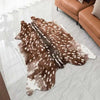 A brown and white faux animal skin rug with a non-slip backing placed on a light gray tile floor.