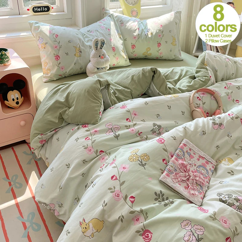 A light green and pink floral duvet cover set with matching pillowcases displayed on a bed.