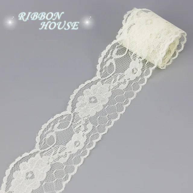 A roll of white decorative lace ribbon, featuring intricate floral patterns and a gathered end.