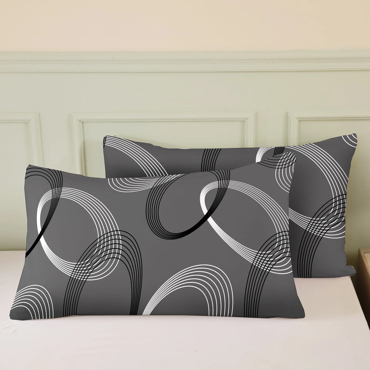 A set of three gray and white patterned pillows displayed on a white bed with light green molding.