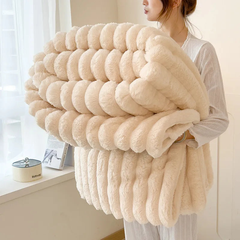 A woman holds a fluffy, cream-colored blanket made of thick, soft wool fibers.