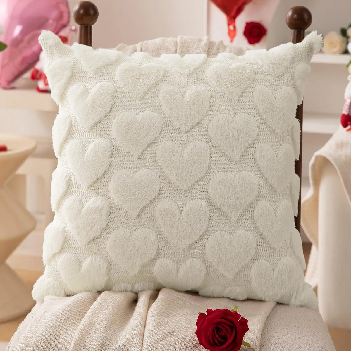 A white heart embroidery plush cushion cover resting on a light-colored fabric.