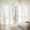 White sheer ruffled lace embroidered curtains framing a bright window and a light wood floor.