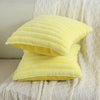 A stack of bright yellow square faux rabbit fur cushion covers resting on a white textured fabric.