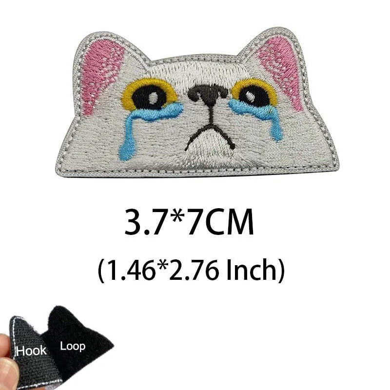 Embroidered tactical patch of a cat face with blue tear streaks on a gray background