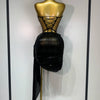 A black, draped performance set displayed on a gold mannequin.