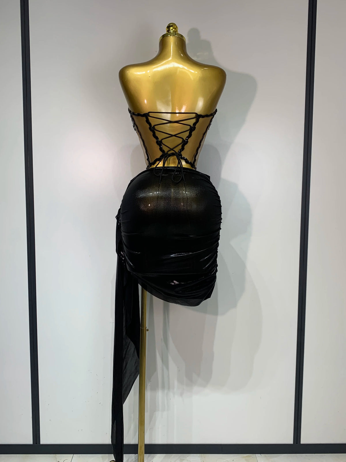 A black, draped performance set displayed on a gold mannequin.