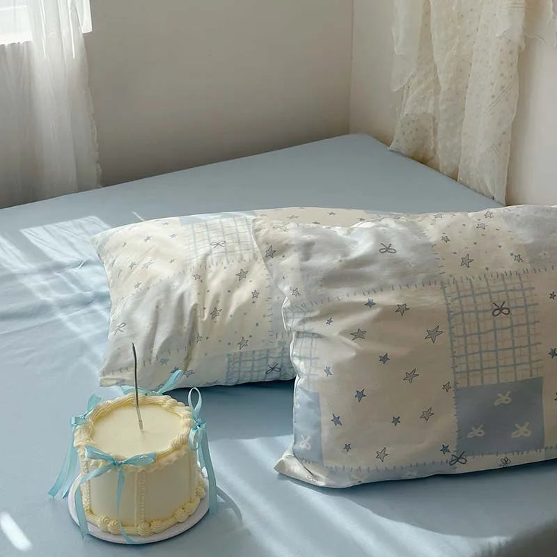 A set of three white and blue floral duvet covers and pillowcases displayed on a light blue bed.