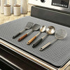 A set of heat-resistant silicone cooking utensils including spatulas and spoons resting on a dark stove top mat.