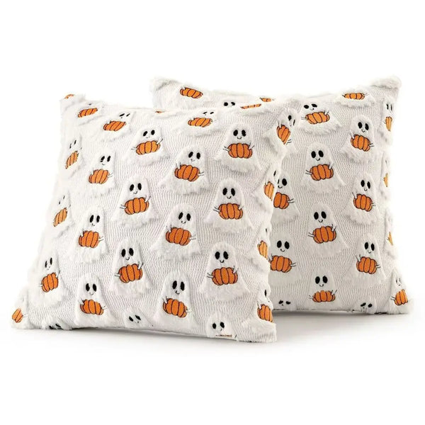 A white throw pillow cover patterned with small orange ghost and pumpkin designs.