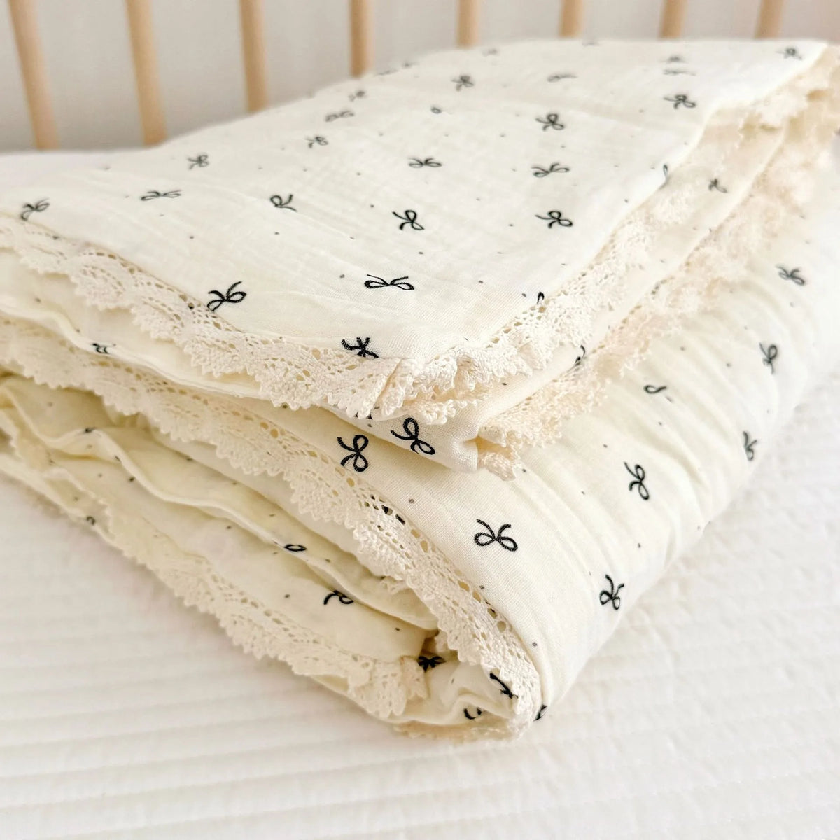 A stack of white muslin blankets with a small floral print pattern is folded on a white surface.