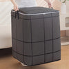 A large, dark gray fabric storage bag with a grid pattern is being held by hands.