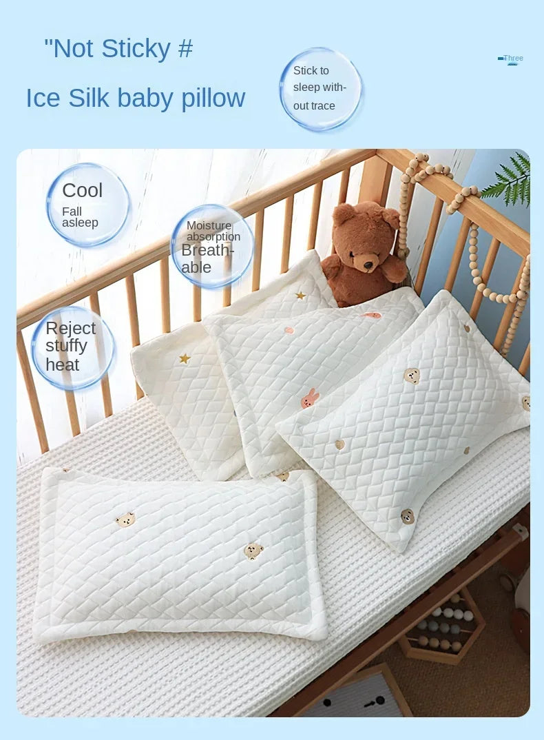 White Ice Silk baby pillow with a teddy bear toy shown on a wooden crib surface.