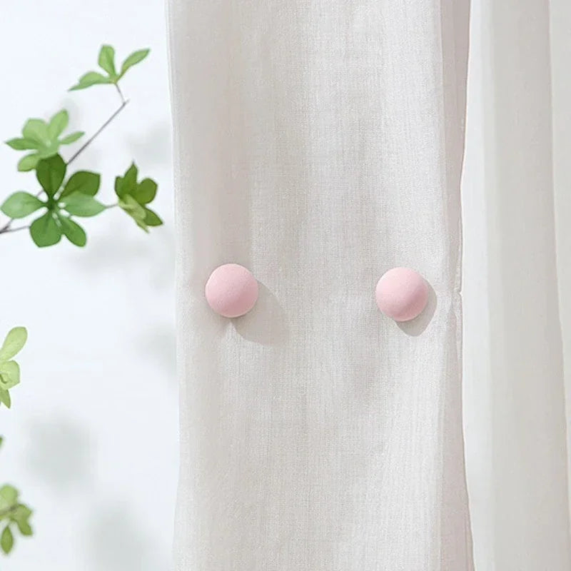 Close-up of a white fabric with two pink round clips used to hold the material.