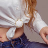 White blouse tied at the waist with gold round heart button clips