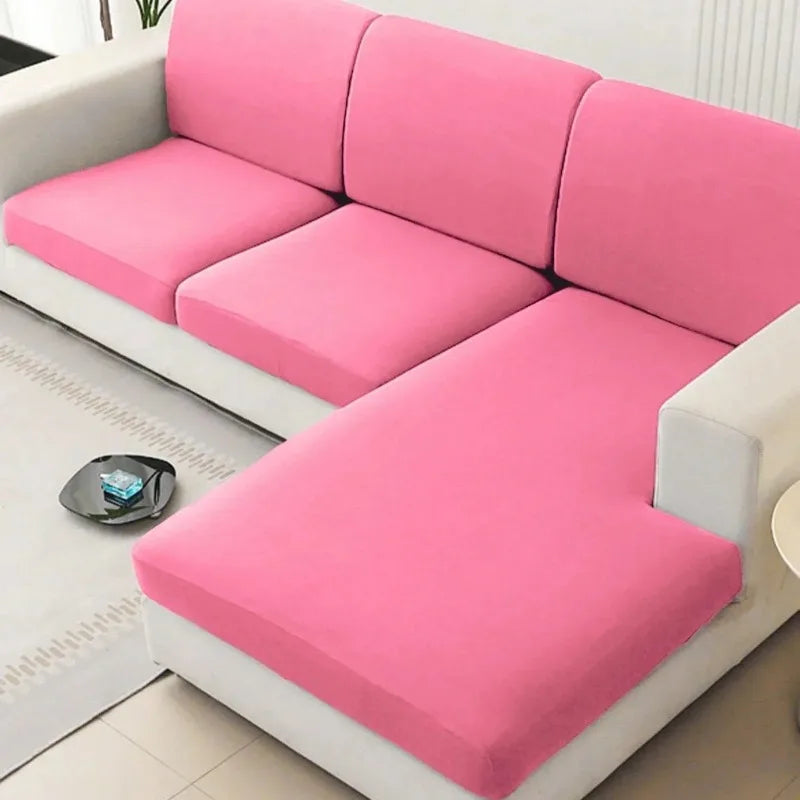 A pink solid elastic sofa cushion slipcover is shown on a white sofa.