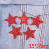 Five red glitter star patches embroidered on light blue denim fabric
