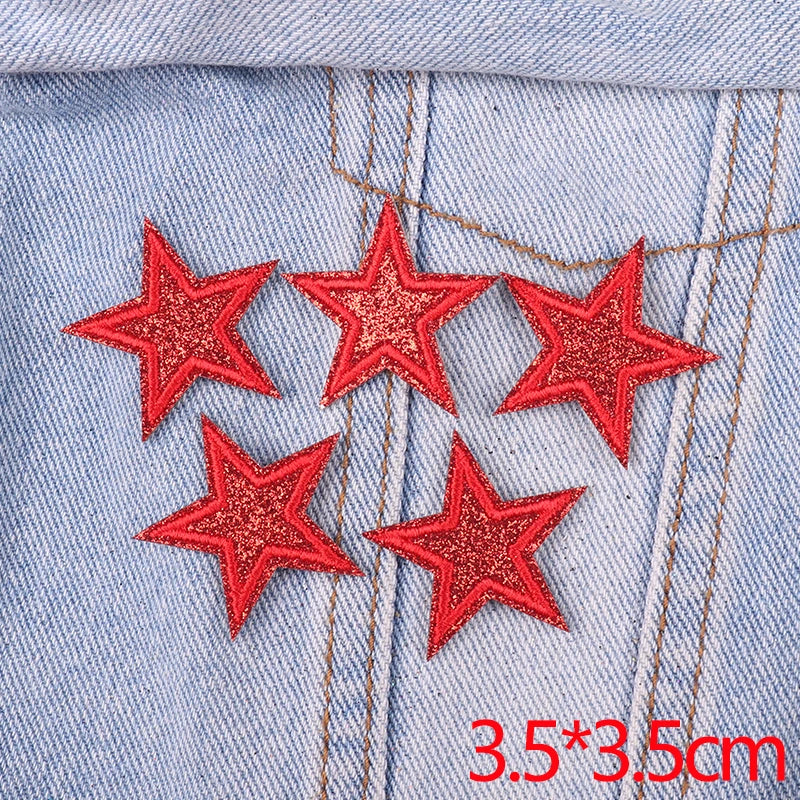 Five red glitter star patches embroidered on light blue denim fabric