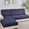 A modern sofa with navy blue slipcovers and light beige trim sits in a bright room next to a framed motivational sign and a w