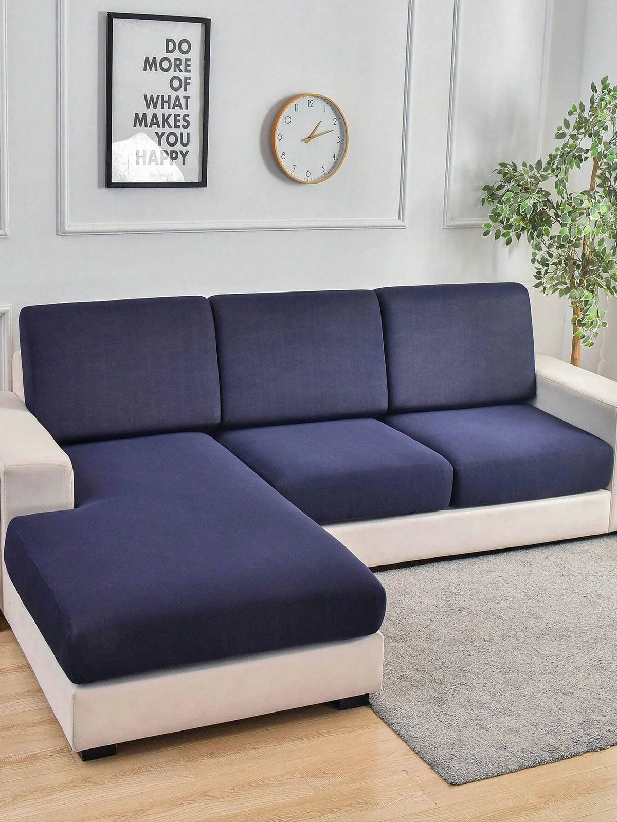 A modern sofa with navy blue slipcovers and light beige trim sits in a bright room next to a framed motivational sign and a w