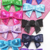 A collection of colorful sequin bow patches and ribbons for DIY decoration displayed on pink paper.