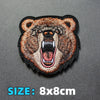 An embroidered patch of a fierce brown bear face with open mouth and teeth on a dark gray background.