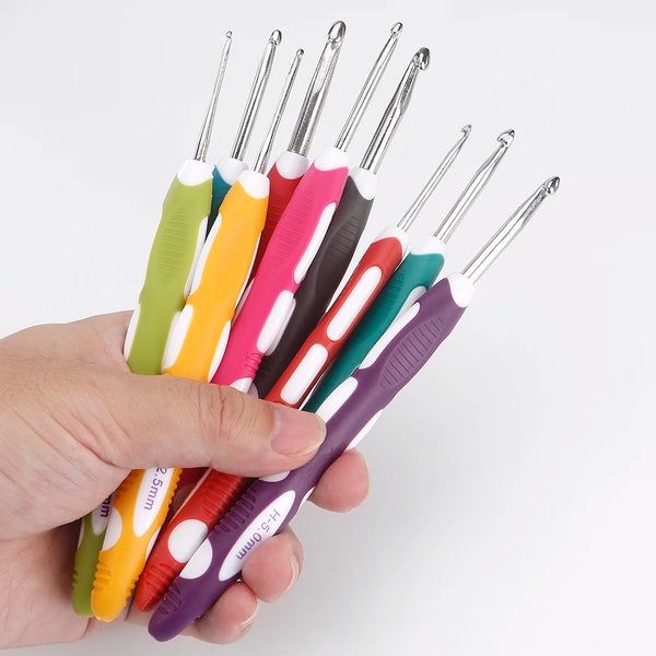 A hand holds a set of various colored DIY crochet hooks for knitting and crafting.