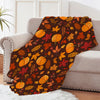 An orange and brown leaf pattern fleece throw blanket draped over a light gray sofa.