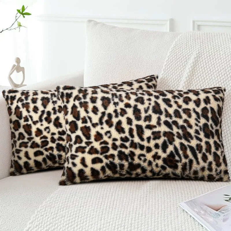 Two leopard print velvet pillow covers resting on a white sofa or bed.