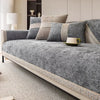 A gray linen sofa cover with matching pillows and a green cup displayed on a light rug.