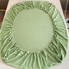 A round green velvet fabric cover for a bed or table, gathered and ruffled.
