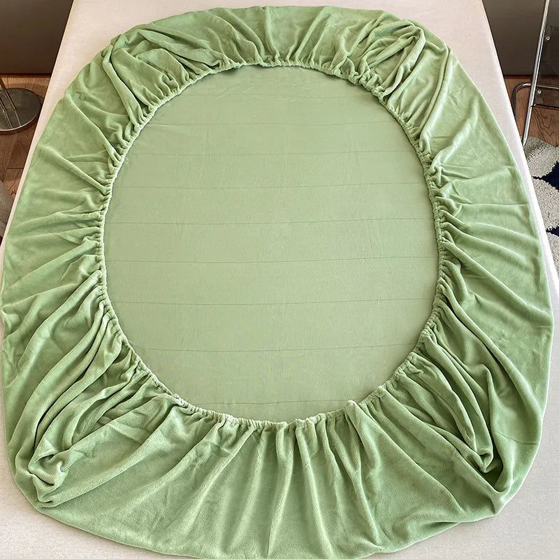 A round green velvet fabric cover for a bed or table, gathered and ruffled.