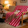 A plush throw blanket featuring C-Curious George on a red and white striped background.