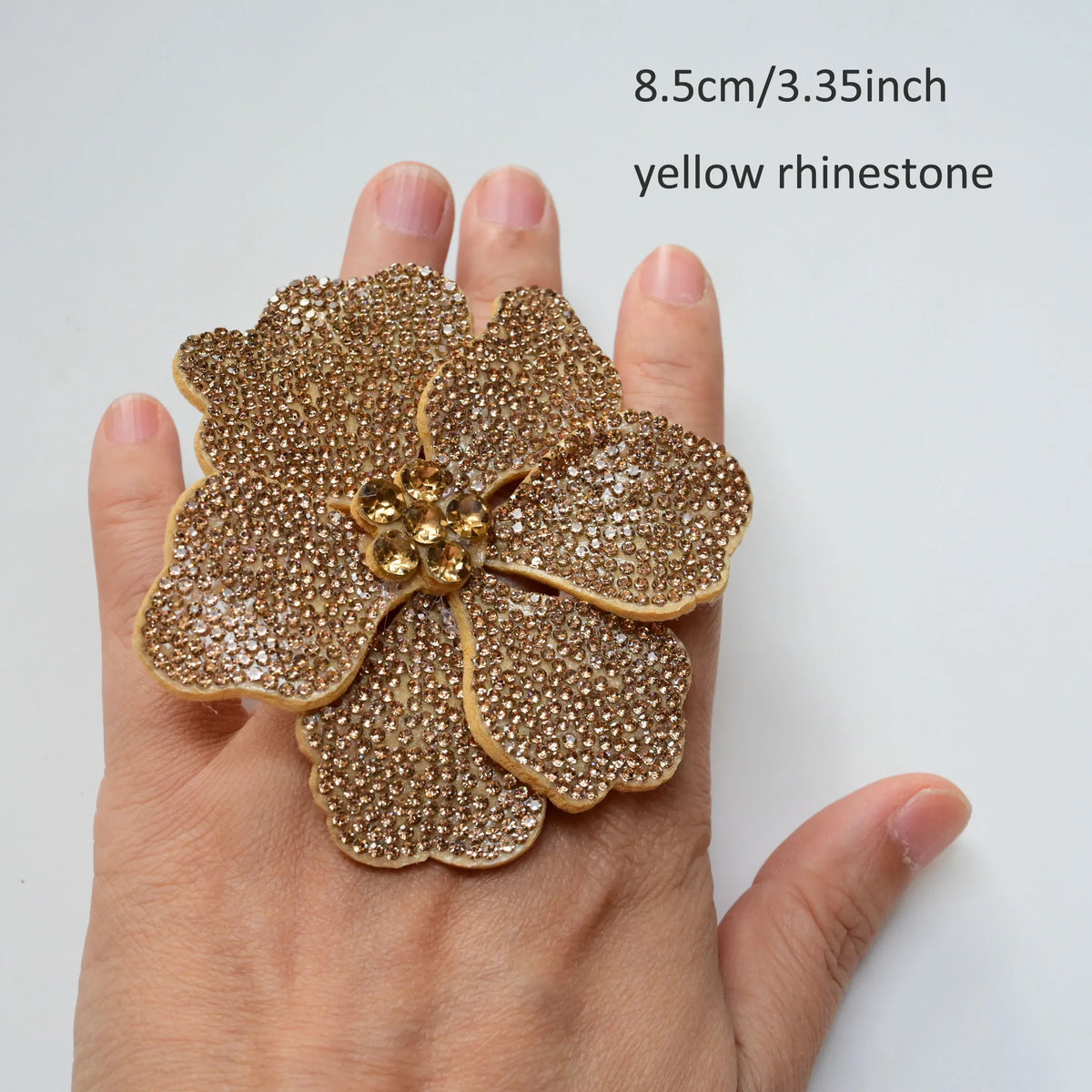 A hand holds a yellow rhinestone flower applique patch, measuring 8.5cm or 3.35 inches.