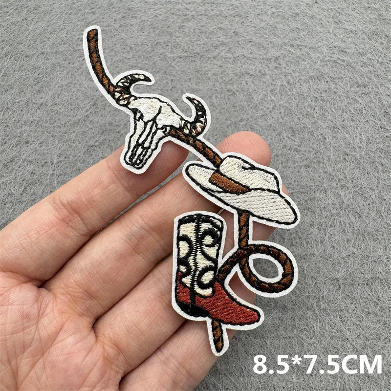 An embroidered patch featuring a skull and a cowboy hat on a brown leather strap.