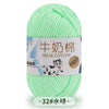 A ball of light green milk cotton yarn with a label indicating the yarn type and thickness.