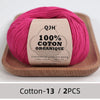 A ball of magenta organic cotton yarn labeled QJH 100% COTON ORGANIQUE resting on a wooden tray.