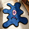 A blue and pink playful one-eye monster shaped area rug on a light floor.