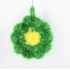 A green sponge with a yellow flower shape is displayed against a white background.