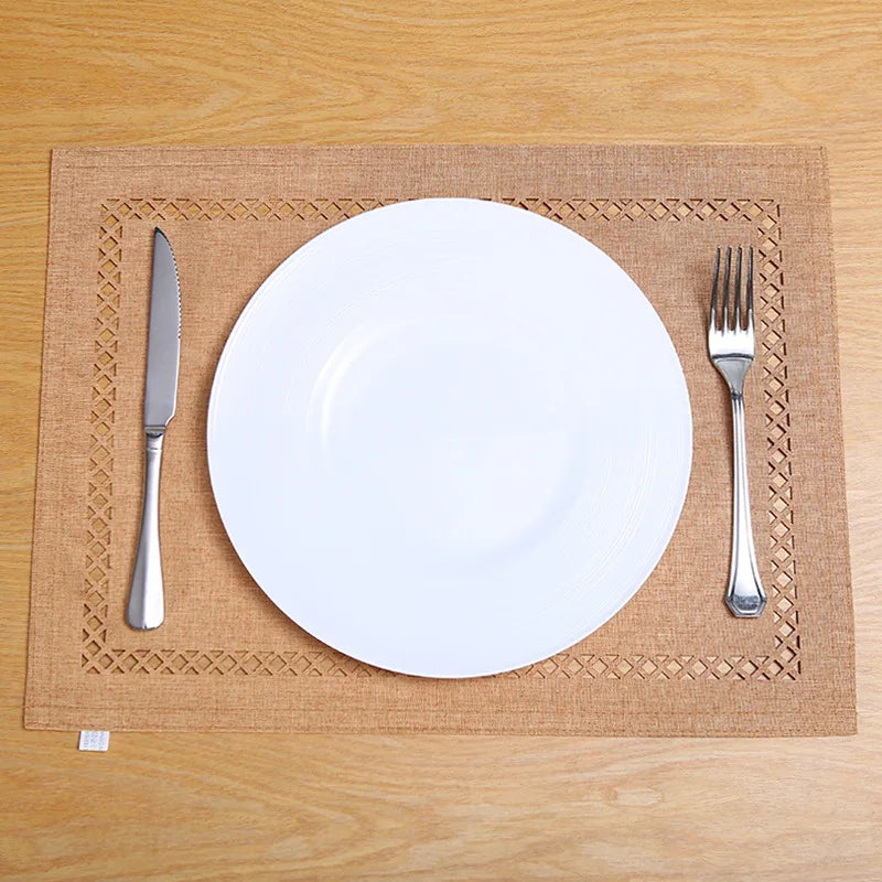 A white dinner plate, fork, and knife are placed on a natural linen placemat on a wooden table.