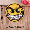 A yellow embroidered patch depicting a menacing, angry face with wide teeth and furrowed brows.