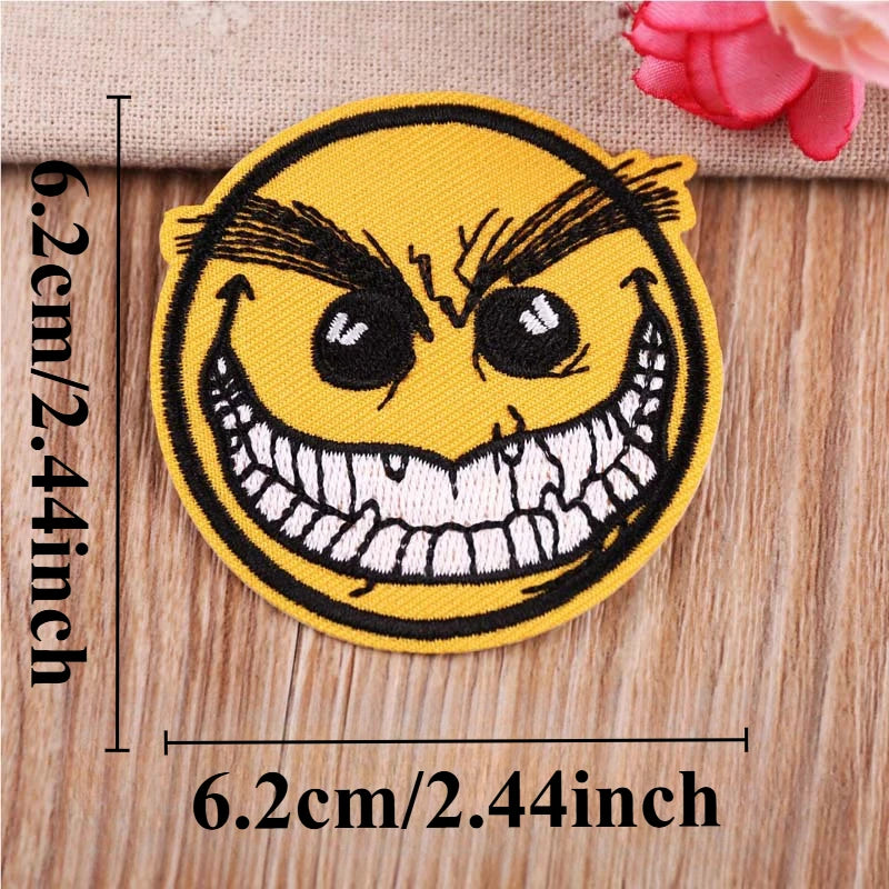 A yellow embroidered patch depicting a menacing, angry face with wide teeth and furrowed brows.