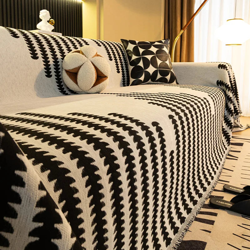 A close-up of a white and black patterned chenille sofa cover with a spherical white tassel decoration.