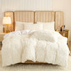 A fluffy white plush duvet cover set displayed on a bed with a neutral upholstered headboard and bedside lamps.