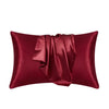 A deep burgundy silk pillow cover with a draped fold, showcasing luxurious fabric texture.
