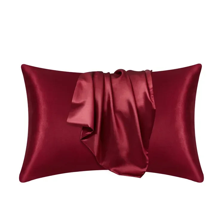 A deep burgundy silk pillow cover with a draped fold, showcasing luxurious fabric texture.